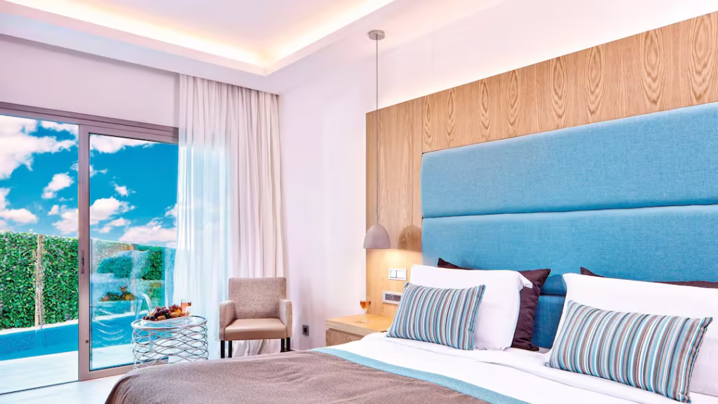 Elegant room at Atlantica Golden Beach Hotel & Resort with king-size bed, modern décor and private balcony overlooking the sparkling Mediterranean Sea.