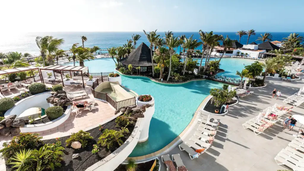 Tropical setting of Hotel Club Jandia Princess featuring palm-lined pool area and ocean views