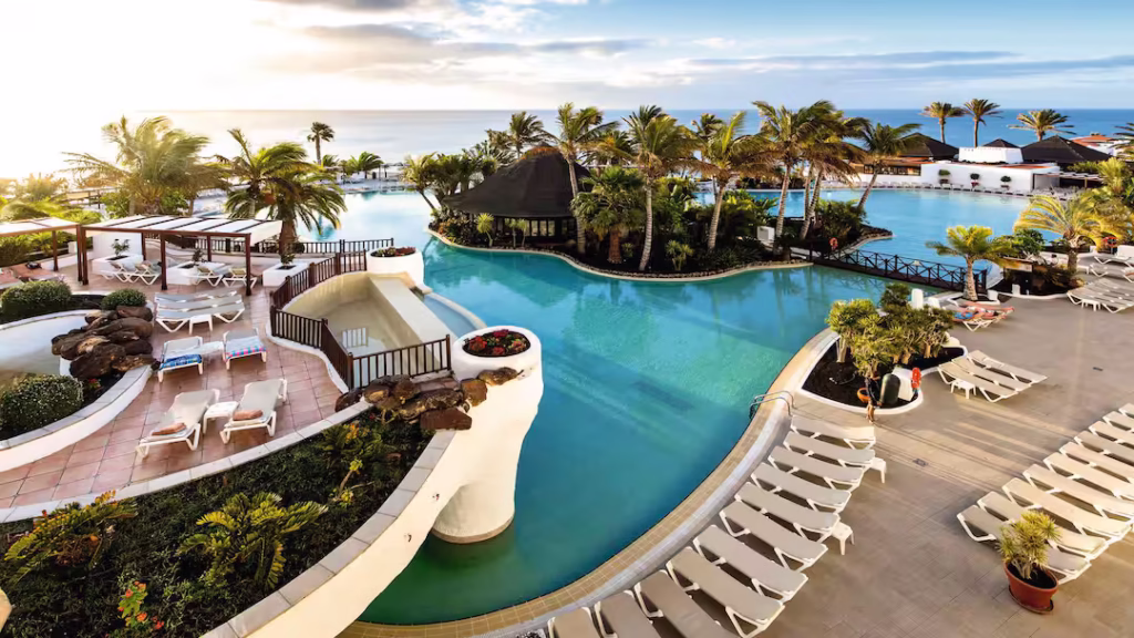 Tropical setting of Hotel Club Jandia Princess featuring palm-lined pool area and ocean views