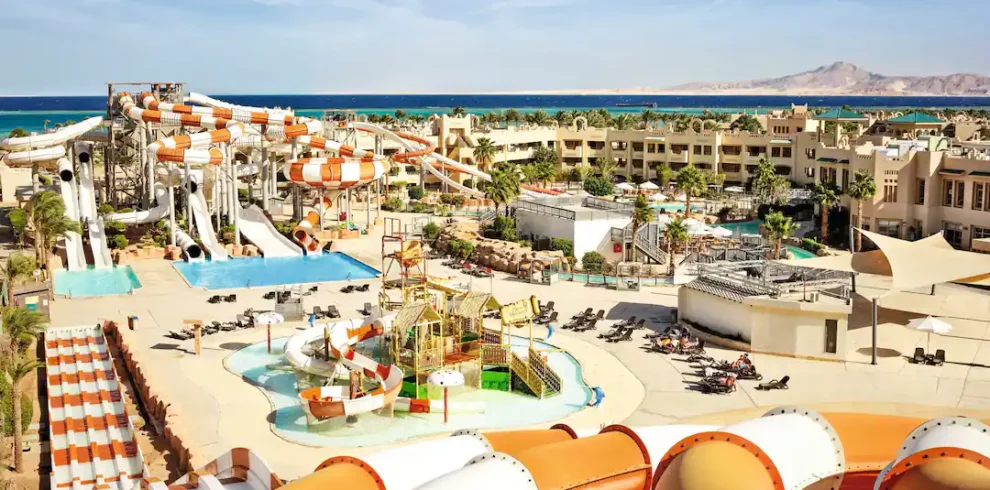 Aerial view of Coral Sea Water World resort showing colourful water slides, swimming pools, lush gardens, and beachfront in Sharm El Sheikh.