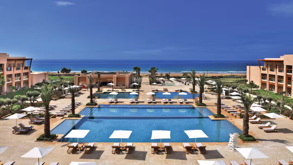 Hilton Taghazout Bay Beach Resort exterior showing sea view, swimming pools and sun loungers