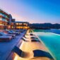 Exterior view of NIKO Seaside Resort MGallery showing poolside chairs partially submerged in clear blue water